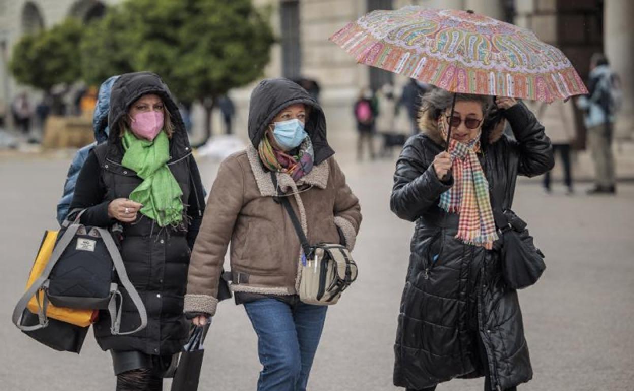 Tres mujeres se protegen de la lluvia