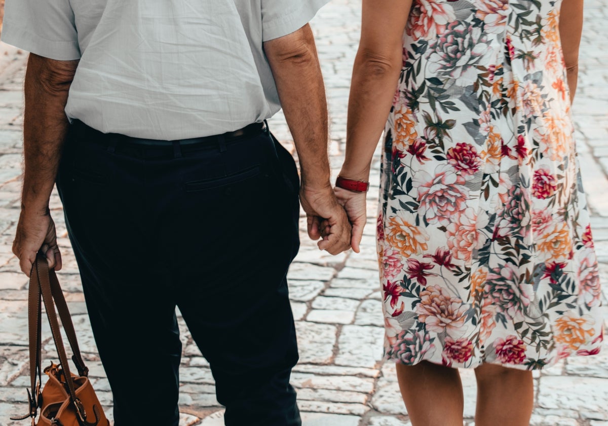 Una pareja de edad avanzada pasea de la mano.