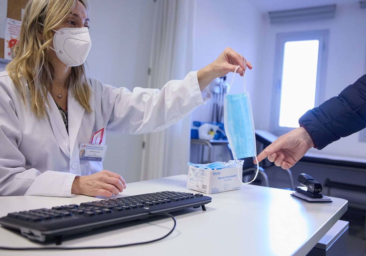 Una enfermera entrega una mascarilla a un paciente.