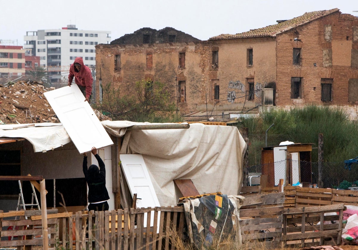 Dos personas reconstruyen una chabola junto a la alquería quemada este viernes.