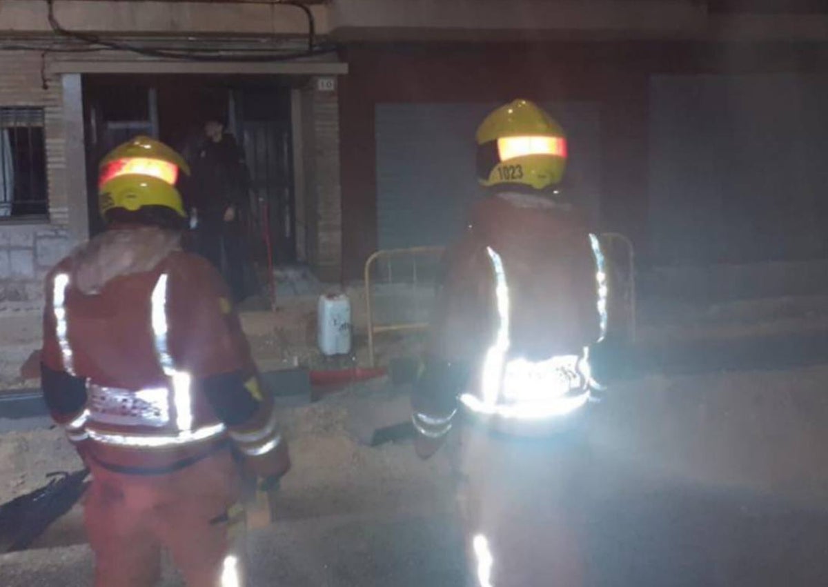 Imagen secundaria 1 - Fachada de la vivienda siniestrada, bomberos en el lugar y la puerta de la casa donde fue hallada sin vida la niña.