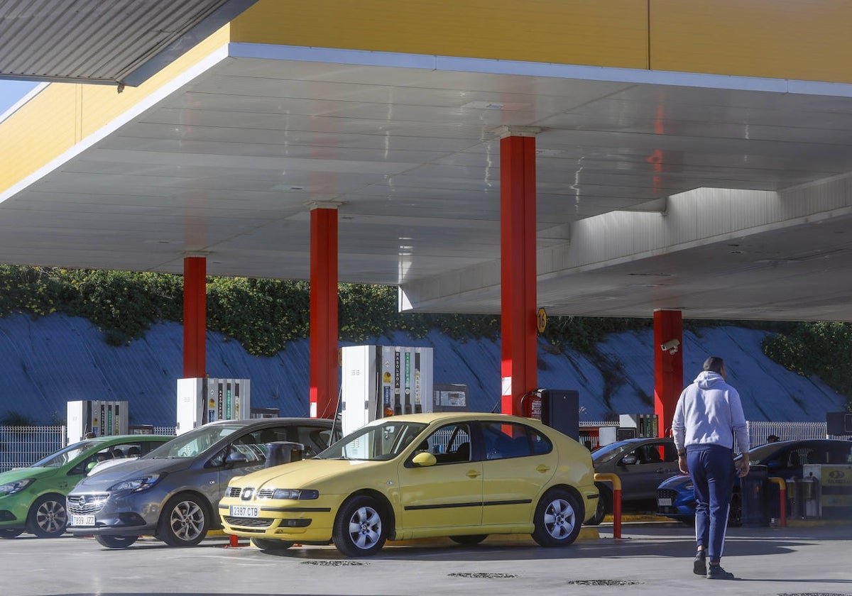 Un hombre camina junto a varios vehículos en una gasolinera de Valencia.