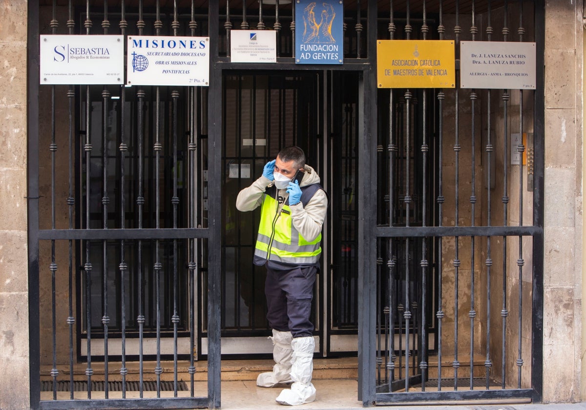 Uno de los investigadores habla por teléfono en la puerta del edificio donde tuvo lugar el crimen.