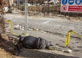 Una persona tumbada en el suelo, en la plaza 7 de Octubre de las Casitas Rosa, ahora en obras.