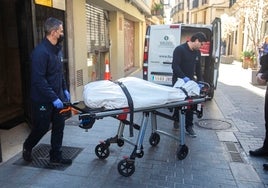 Dos trabajadores del retén fúnebre trasladan el cadáver de la víctima.