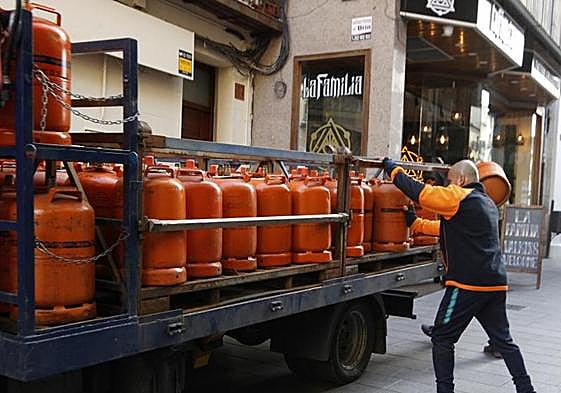 Un hombre carga una bombona de butano en su coche.