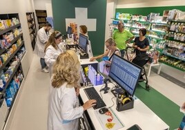 Farmacéuticos atienden a clientes en un establecimiento.