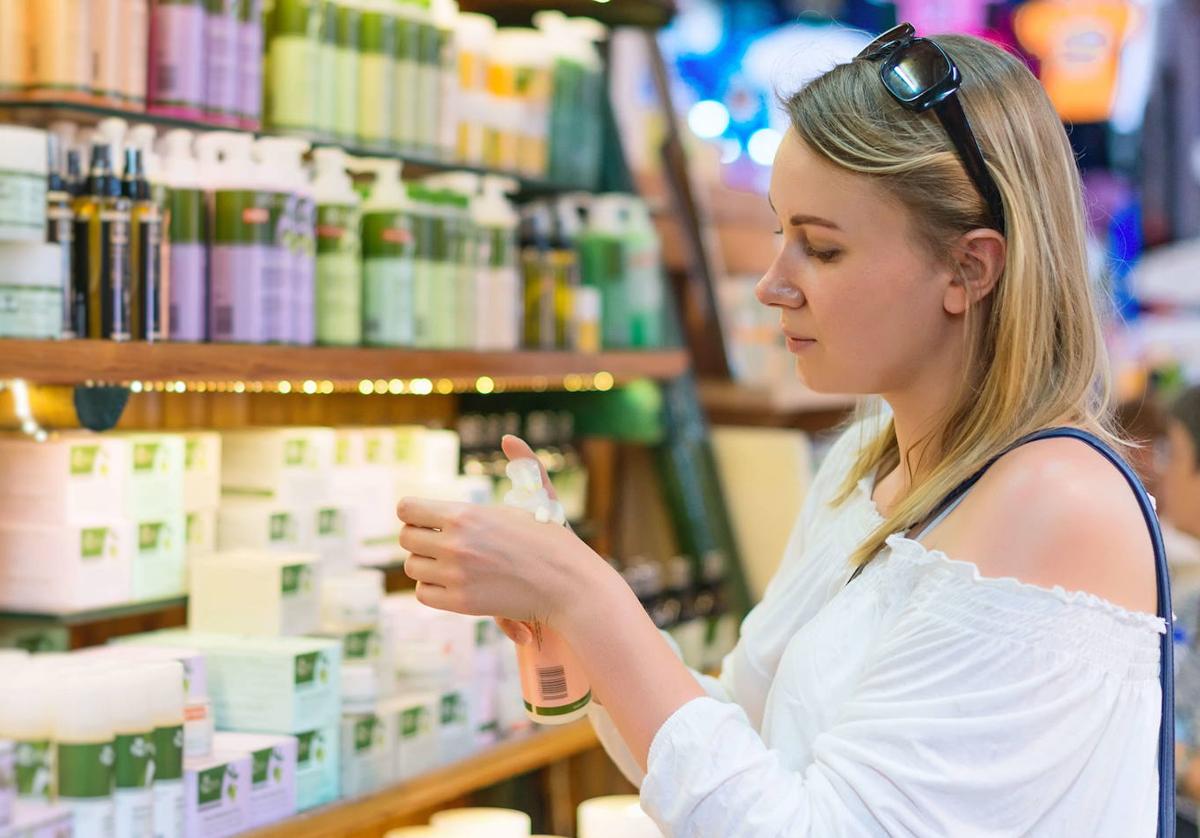 Una mujer prueba cremas en una tienda de cosméticos.