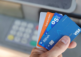 Un usuario con varias tarjetas de crédito en un cajero.