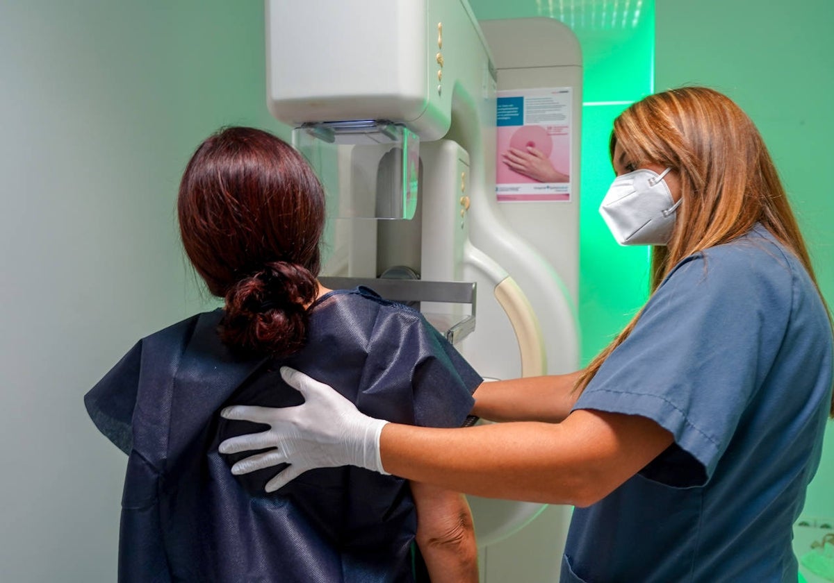 Una paciente junto a una sanitaria en una mamografía.