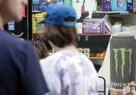 Un joven, junto a un anuncio de bebidas energéticas.