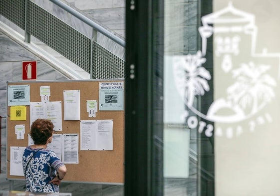 Una mujer frente al tablón de anuncios de un instituto valenciano.