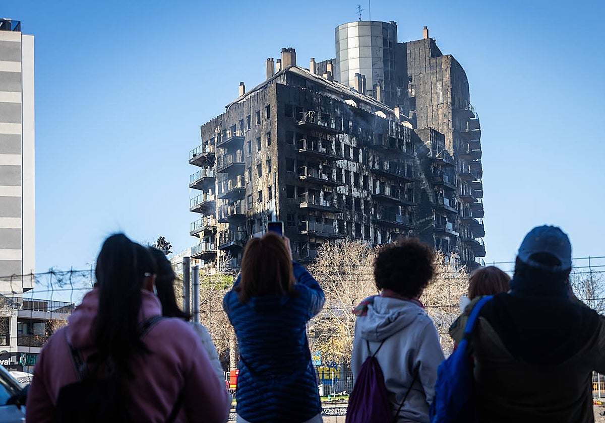 Varias personas observan el edificio de Campanar, este viernes.