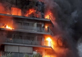 Una pareja permanece en el balcón de una vivienda a la espera de ser rescatada por los bomberos, en el incendio de este jueves en Campanar.