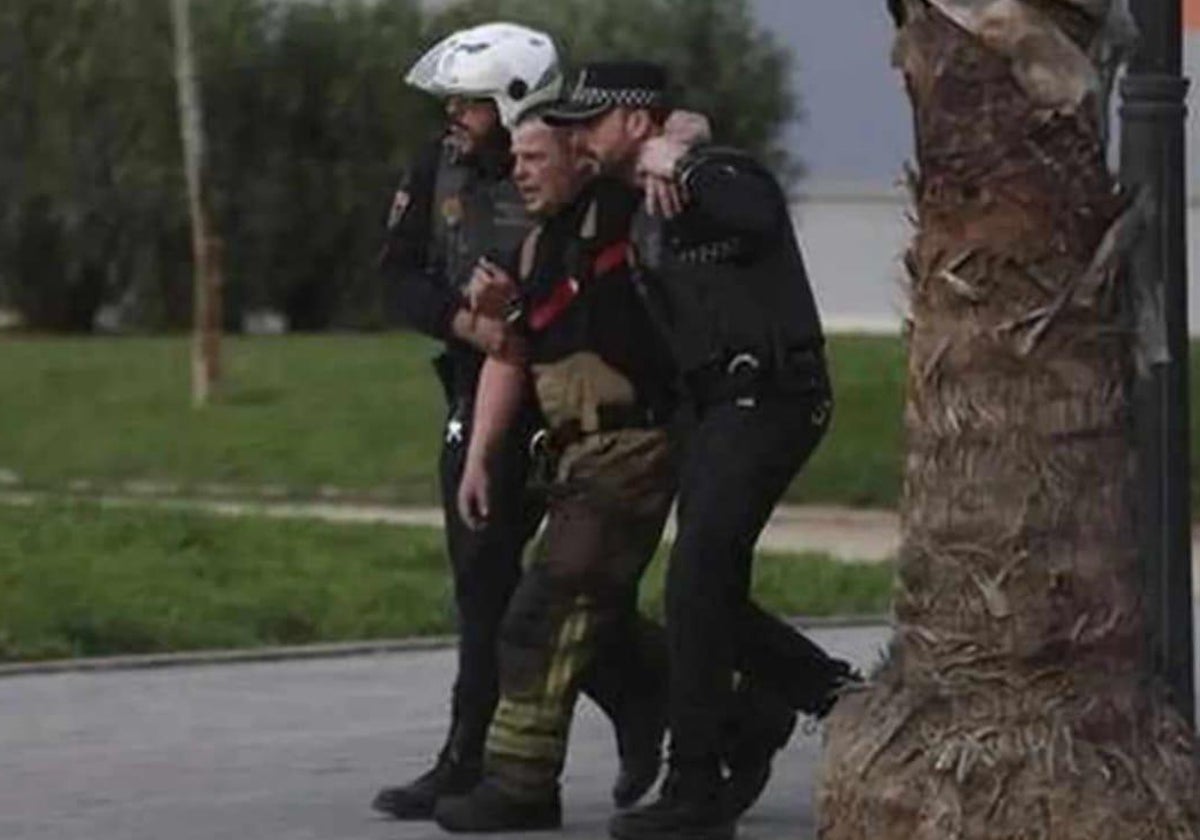 Dos policías locales auxilian a uno de los bomberos heridos.