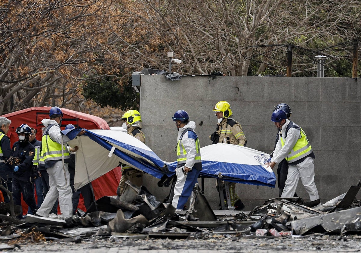 Agentes de Policía Científica y bomberos cubren el cuerpo del último cadáver hallado.