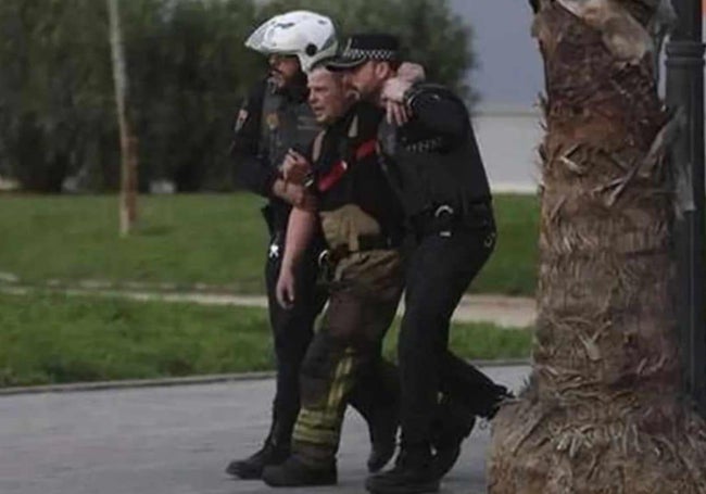 Dos policías locales auxilian a un bombero herido.