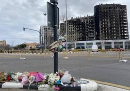 Flores, velas y algún peluche depositados ante el edificio incendiado.