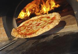 Una persona sacando una pizza del horno.