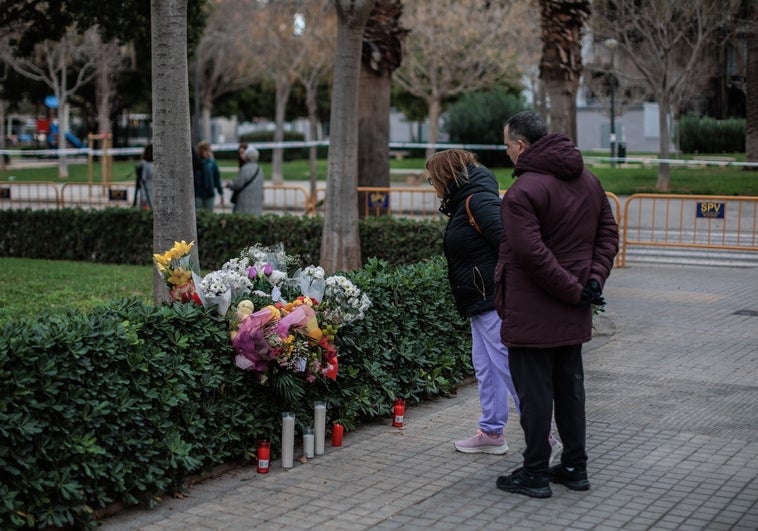 Una pareja observa un ramo de flores depositado en recuerdo a las víctimas del incendio de Campanar.