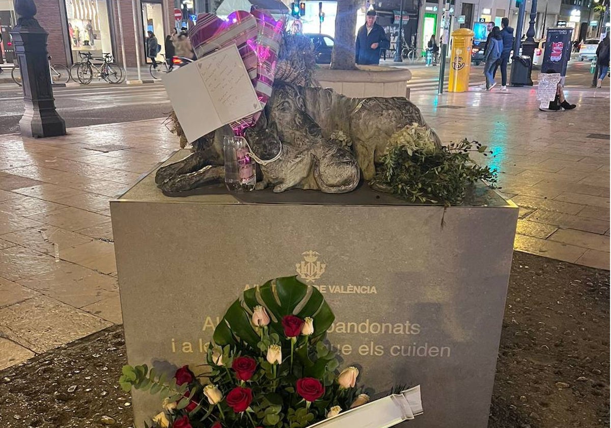 La corona de flores al pie de la escultura.