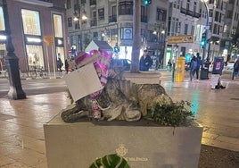 La corona de flores al pie de la escultura.