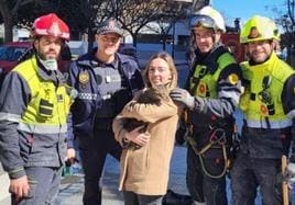Andrea posa con 'Coco', los bomberos y el policía que han encontrado al gato.