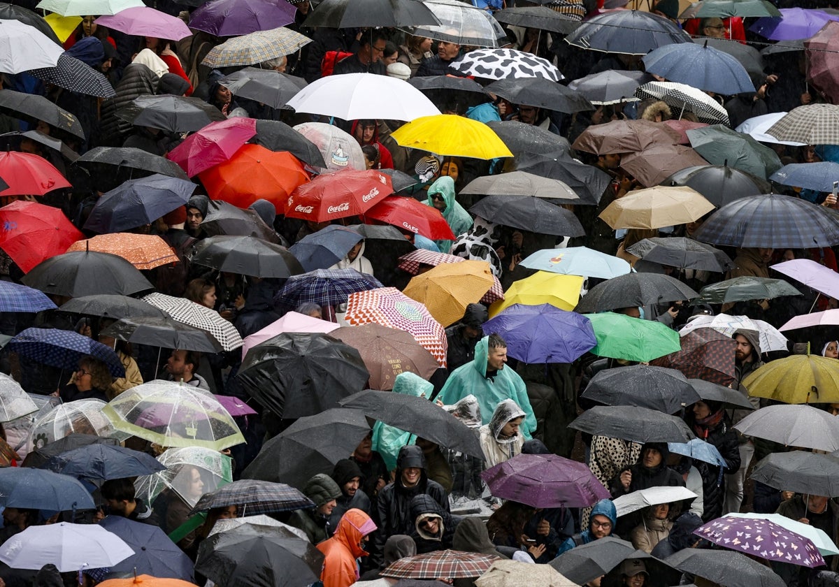 Los asistentes a la mascletà de este sábado, protegiéndose del agua.