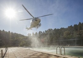 Un helicóptero recarga agua en una piscina.