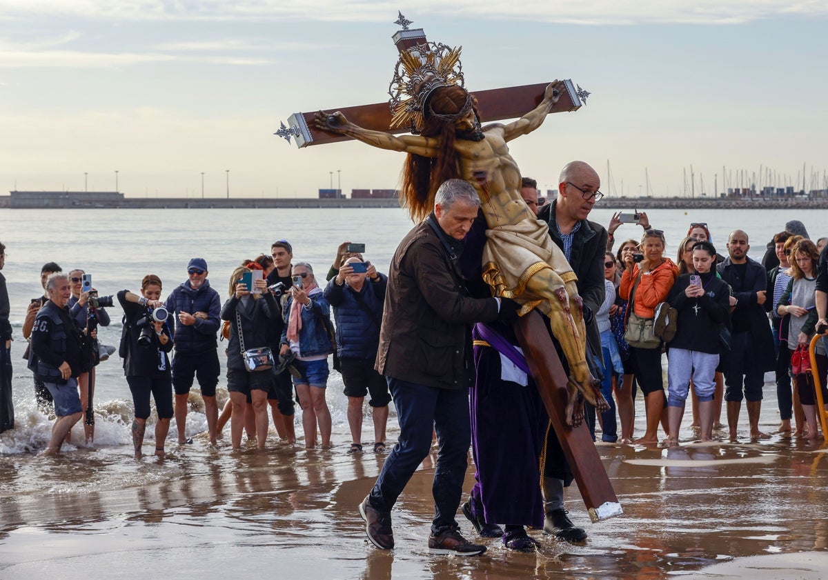 Imagen principal - Visita a la playa y ofrenda de la corona de laurel y una devota, pasando un pañuelo al Cristo.