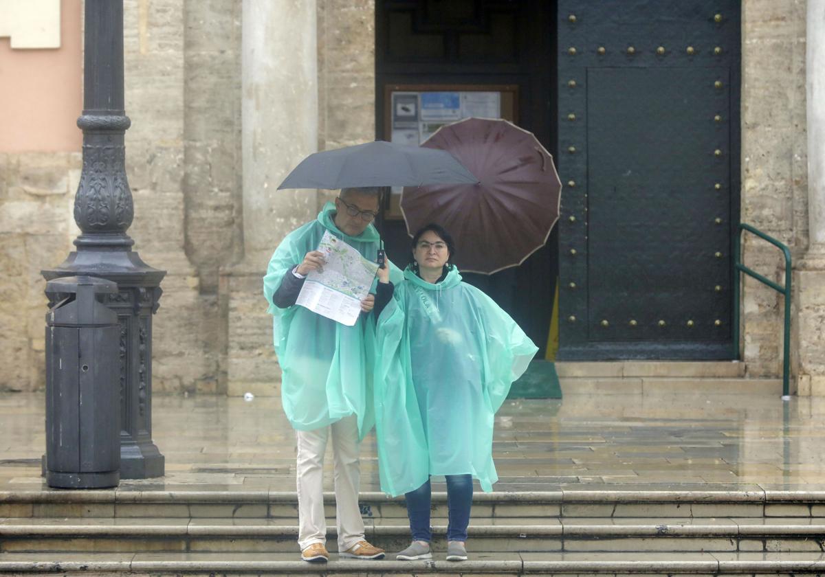 Dos turistas se refugian de la lluvia en una imagen de archivo.