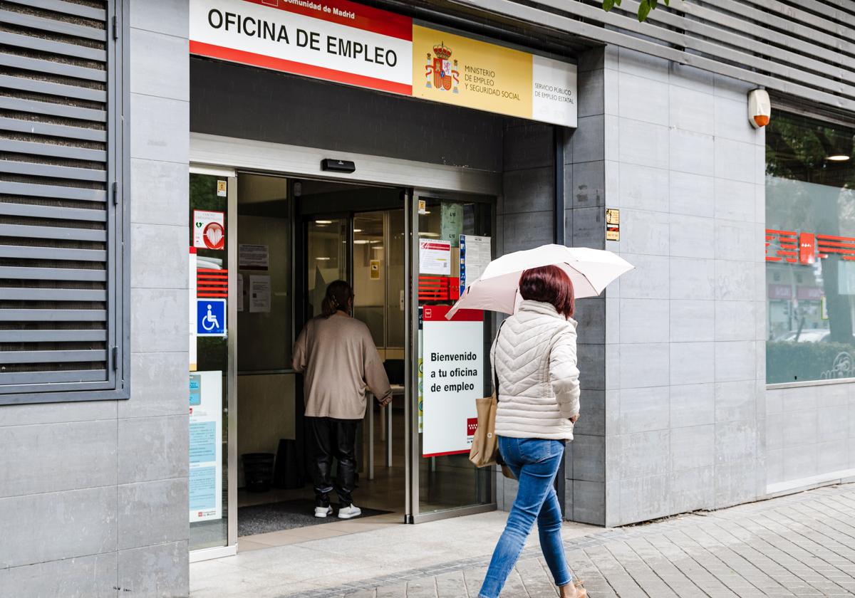 Una mujer con paraguas pasa por la oficina del paro en una imagen de archivo.