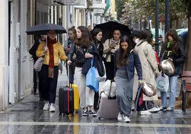 Visitantes con paraguas y maletas por Valencia en esta Semana Santa.