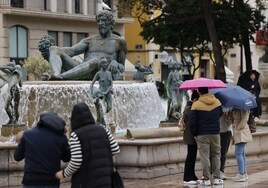 Viandantes se protegen de la lluvia en Valencia.