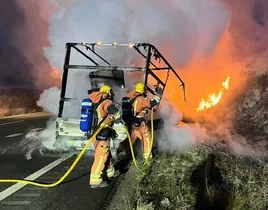 Momento en el que los bomberos extinguen el fuego provocado por el camión incendiado.