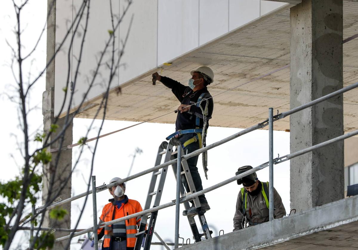 Tres operarios trabajan en una obra.