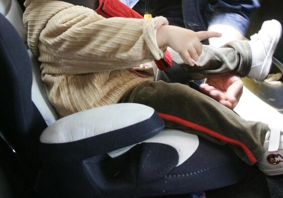 Un niño sentado en una silla homologada para coche.