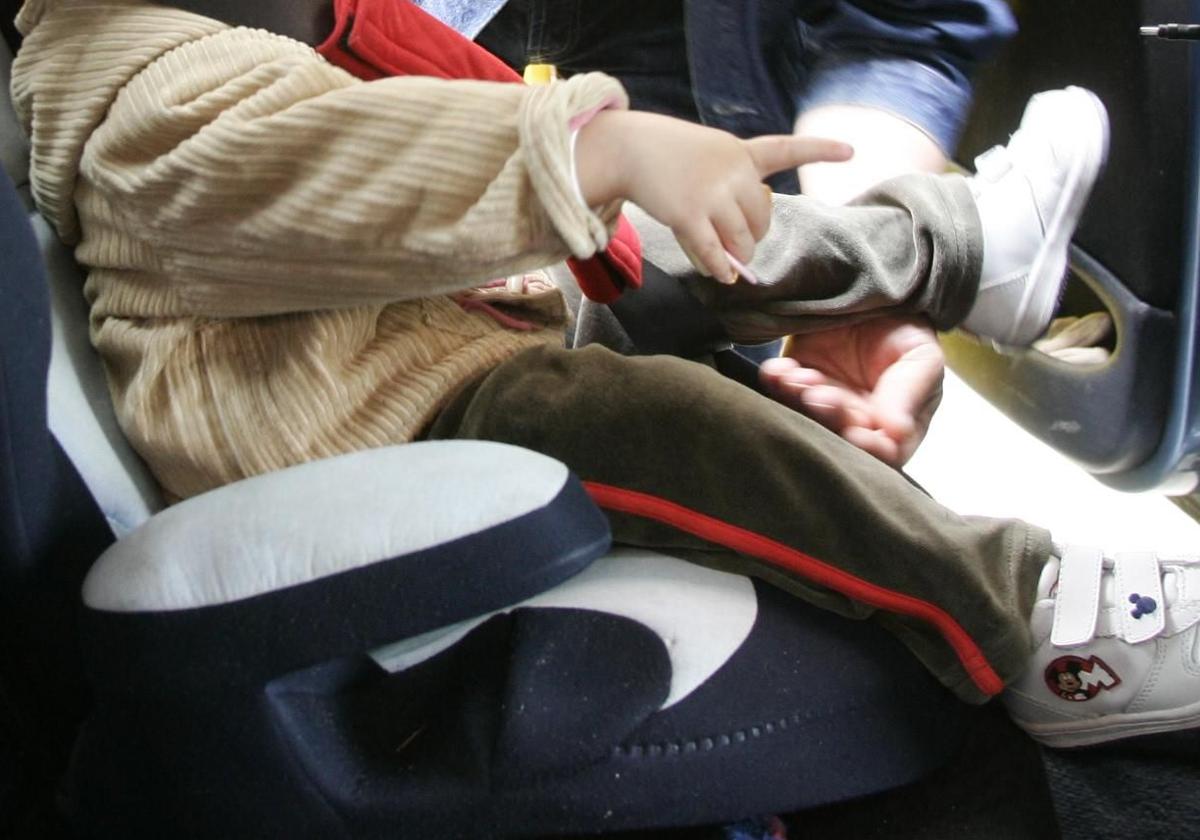 Un niño sentado en una silla homologada para coche.