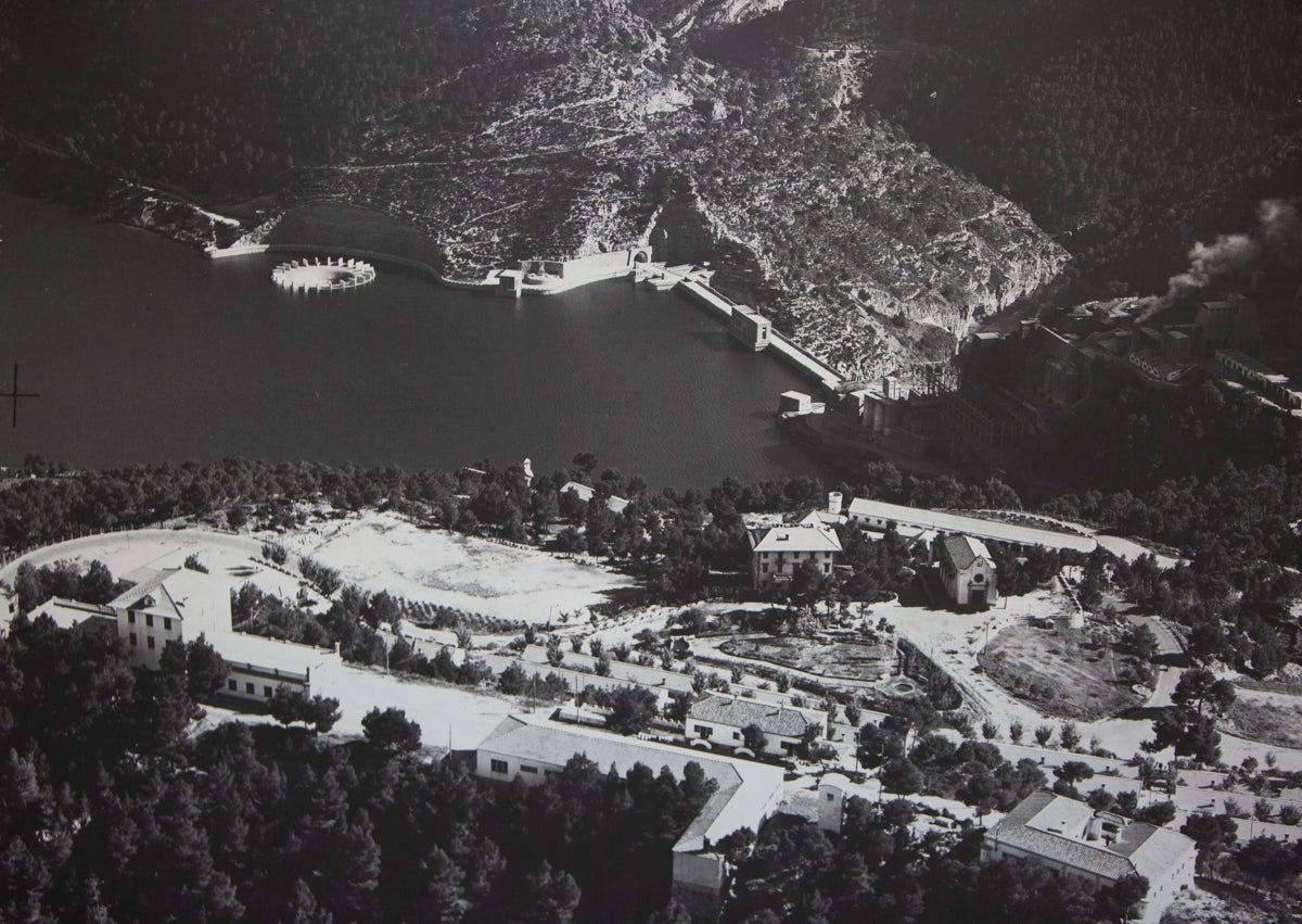 Imagen secundaria 1 - Eva Tejedor muestra una imagen que recuerda cómo era el aspecto de la plaza del antiguo San Antonio de Benagéber, cuyo ayuntamiento preside; sobre estas líneas, dos fotos en blanco y negro del viejo embalse.