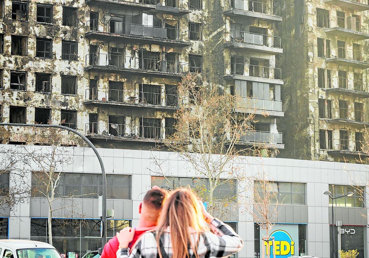 Una pareja contempla el edificio calcinado de Campanar.