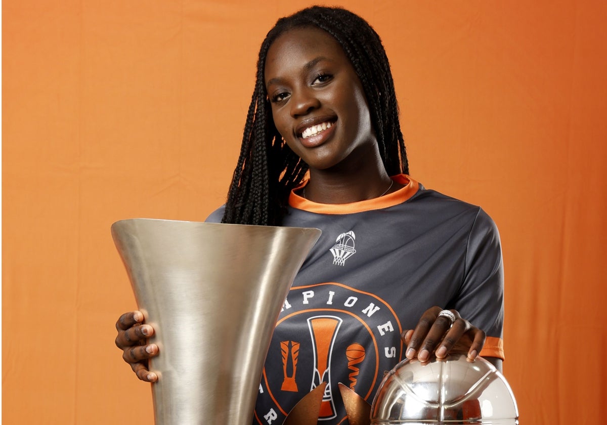 Awa Fam posa con los tres trofeos ganados por el Valencia Basket esta temporada.