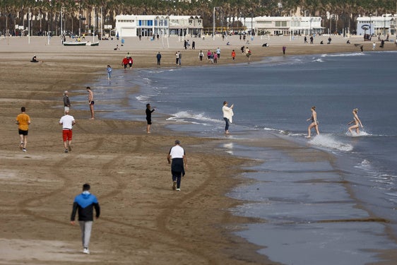 Varias personas disfrutan del buen tiempo en la playa de la Malvarrosa