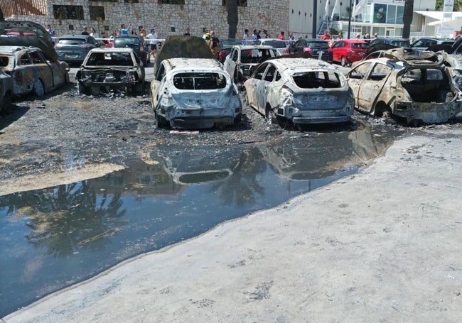 Estado de algunos de los coches calcinados en el incendio, junto a un gran charco por el agua empleada para la extinción.