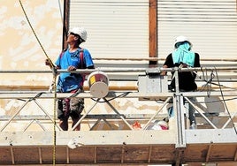 Dos trabajadores en un andamio en una finca ubicada en Valencia.