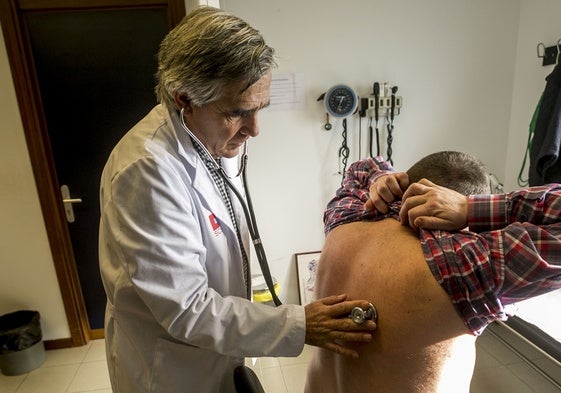 Un médico de familia usa el fonendoscopio con un paciente.