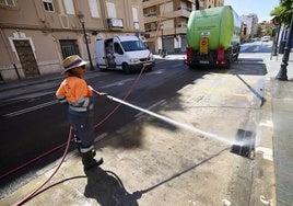 Una operaria limpia un imbornal en una calle de Valencia.