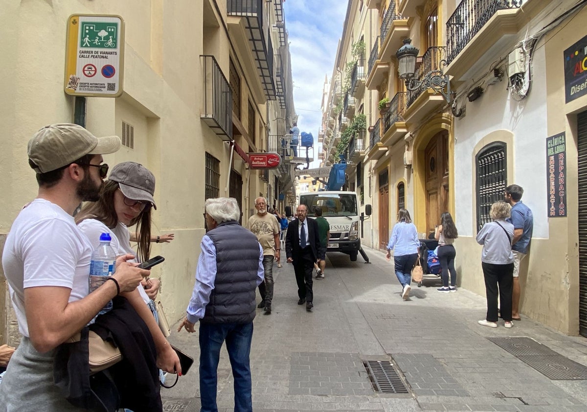 Imagen principal - Turistas viendo el montaje en la calle Vabillers; Pepe Camany entregando cubos a un vecino, Quique Sancho, y proceso de instalación de las cuerdas en los balcones.