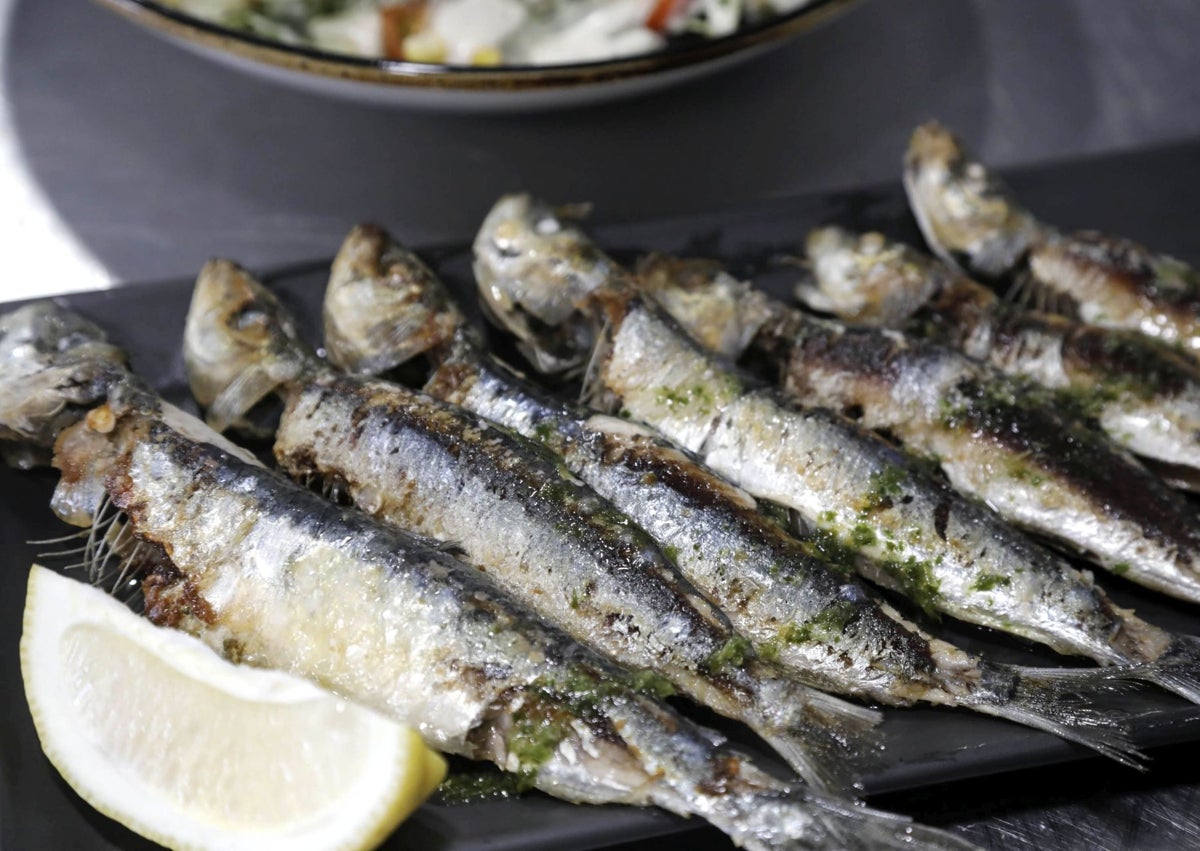 Imagen secundaria 1 - La cocina del restaurante con varias paellas individuales en marcha, una ración de sardinas y el joven Eric con una ensalada con palomitas dulces.
