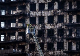 Los bomberos inspeccionan la fachada del edificio incendiado.