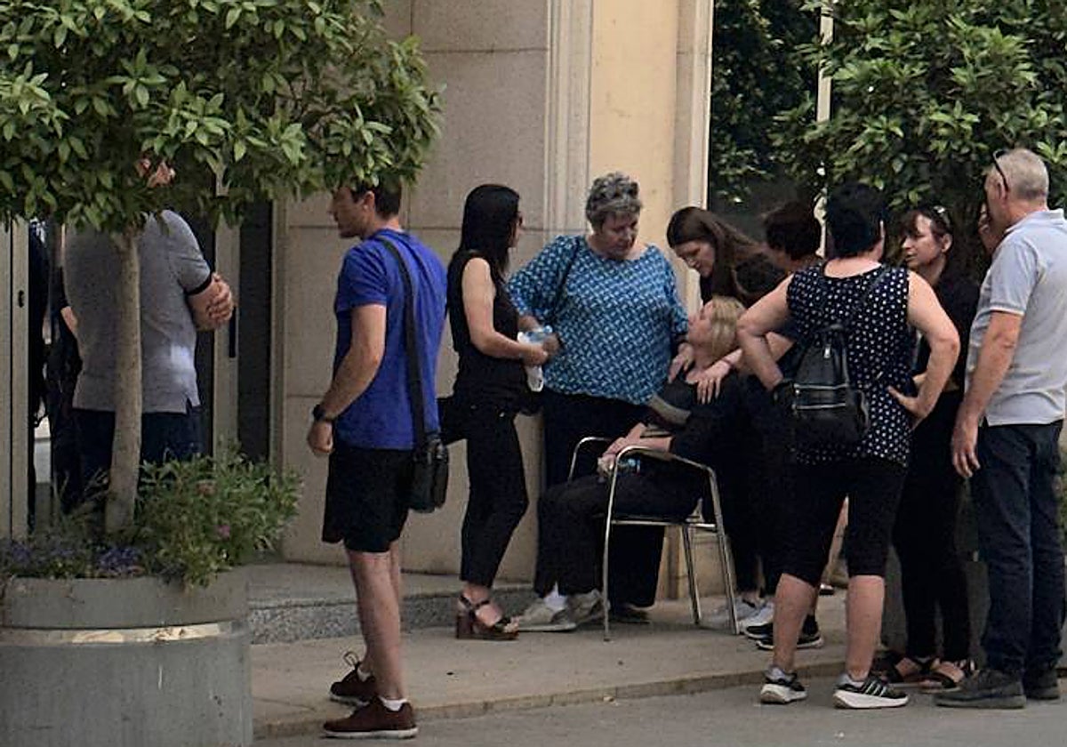 Un grupo de personas consuelan a las hermanas de la mujer asesinada.